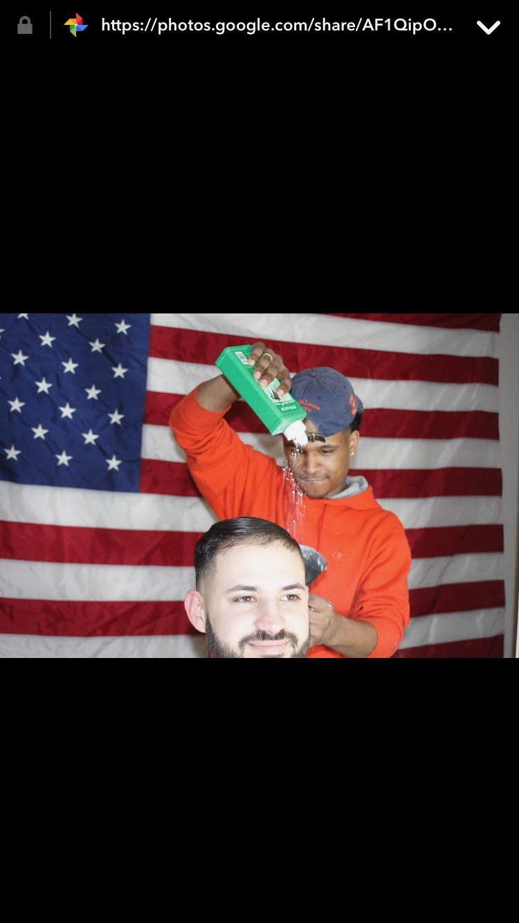 Rommell cutting hair with American flag backdrop